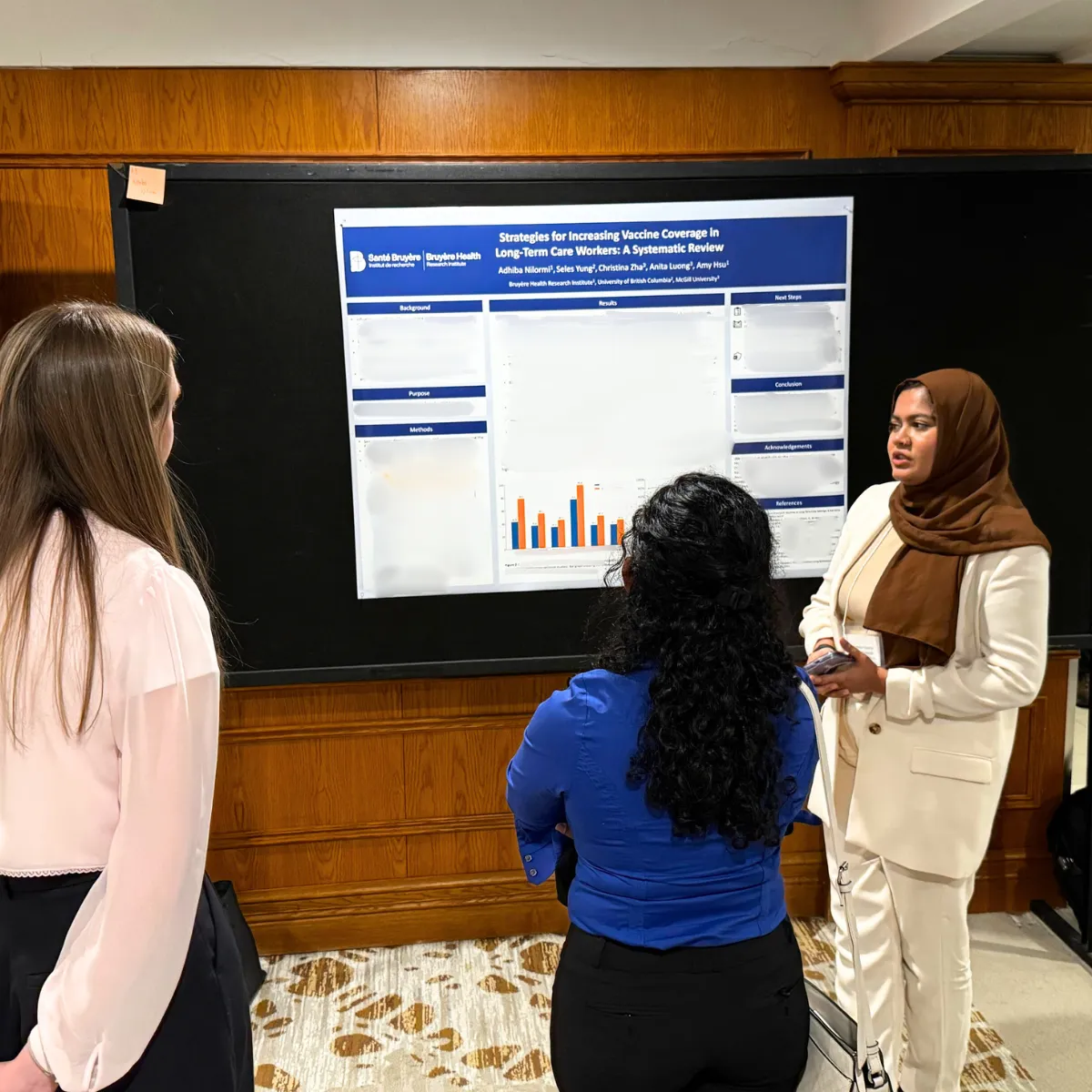 A trainee presents her research poster to two colleagues at the CIRN Annual General Meeting.