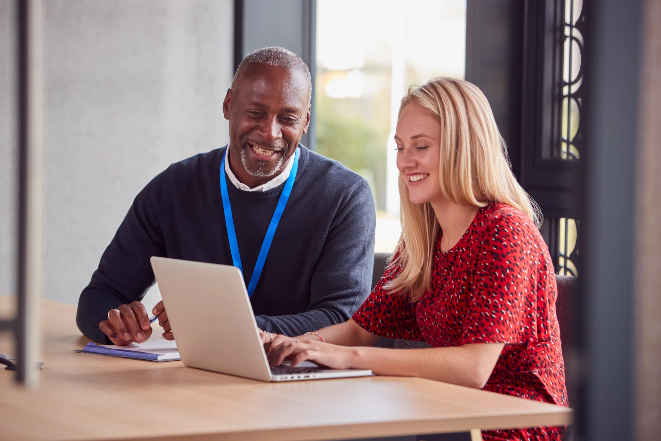A mentor guiding a trainee at a laptop