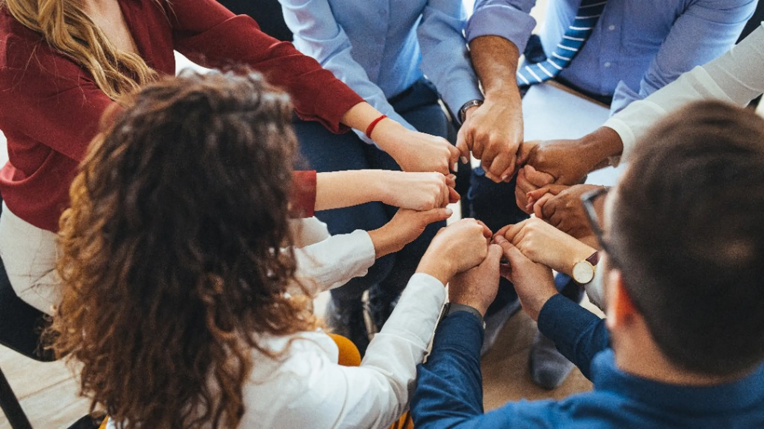 A diverse group of colleagues joining hands in a circle