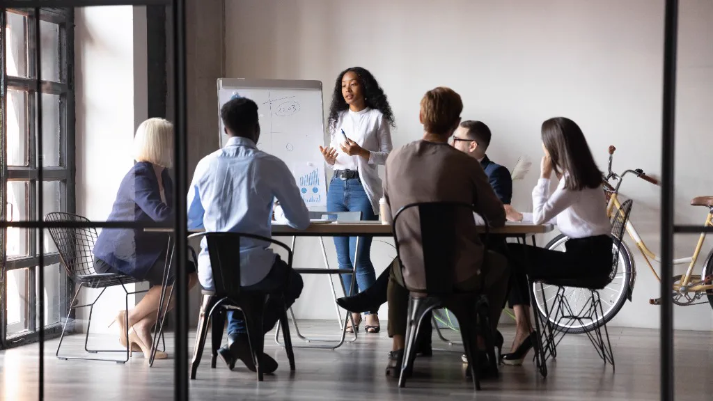 A researcher presenting to colleagues around a meeting table