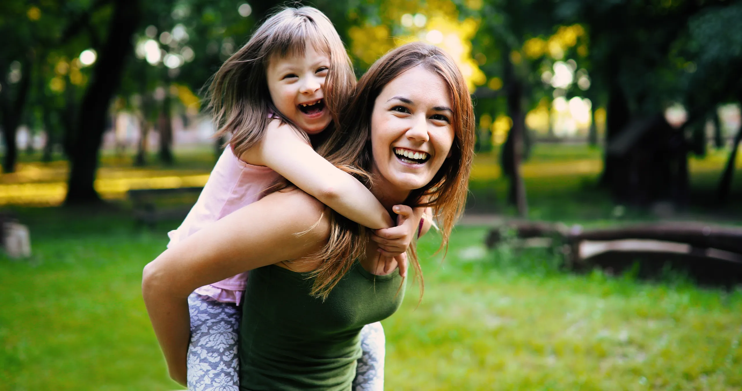 A parent and child laughing together outdoors in a park